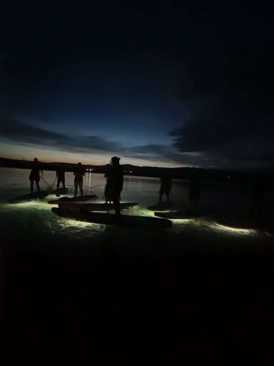 Nasvícený paddleboard na tmavé hladině jezera