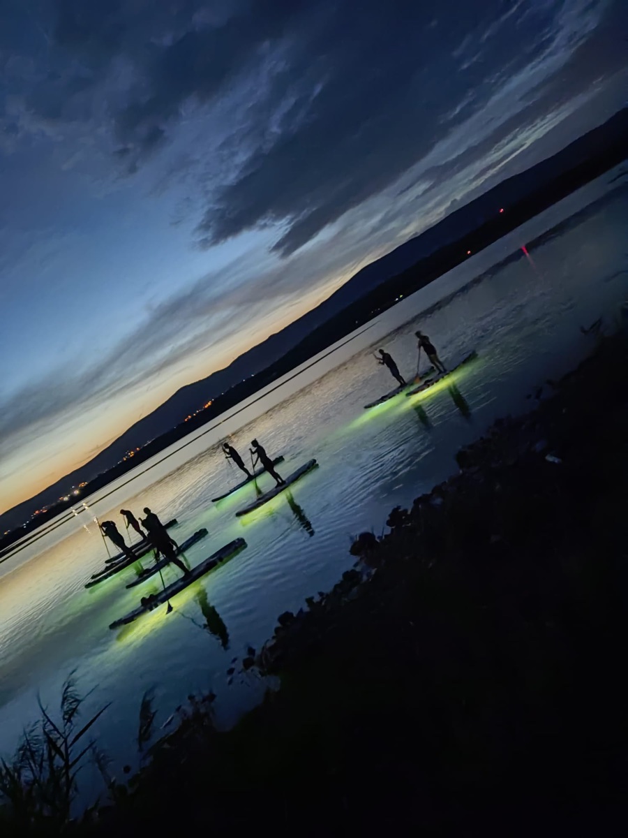 Paddleboardy se světly na jezeře při soumraku